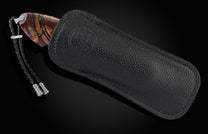 Candcrafted pocket knife from William Henry featuring hand-engraved grouse and quail with copper and 24K gold inlaid with fossil Woolly Mammoth tusk and set with spinel gem stones.. The blade is hand-forged damascus steel.