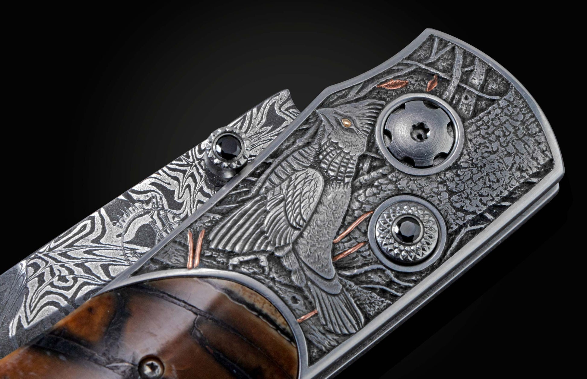 Candcrafted pocket knife from William Henry featuring hand-engraved grouse and quail with copper and 24K gold inlaid with fossil Woolly Mammoth tusk and set with spinel gem stones.. The blade is hand-forged damascus steel.