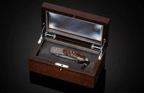 Candcrafted pocket knife from William Henry featuring hand-engraved grouse and quail with copper and 24K gold inlaid with fossil Woolly Mammoth tusk and set with spinel gem stones.. The blade is hand-forged damascus steel.