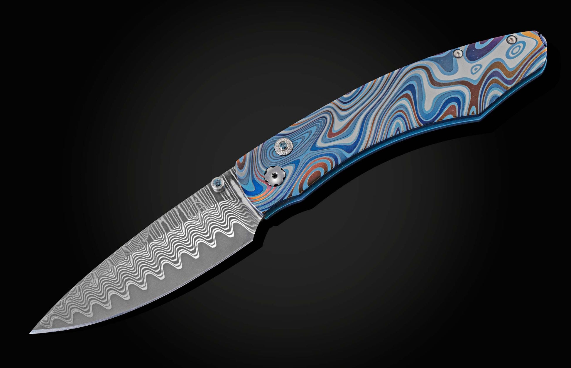 Unique pocket knife from William Henry in swirling colors on laser-engraved titanium with hand-forged damascus blade and blue topaz gemstones. The knife is displayed fully open on a black background.