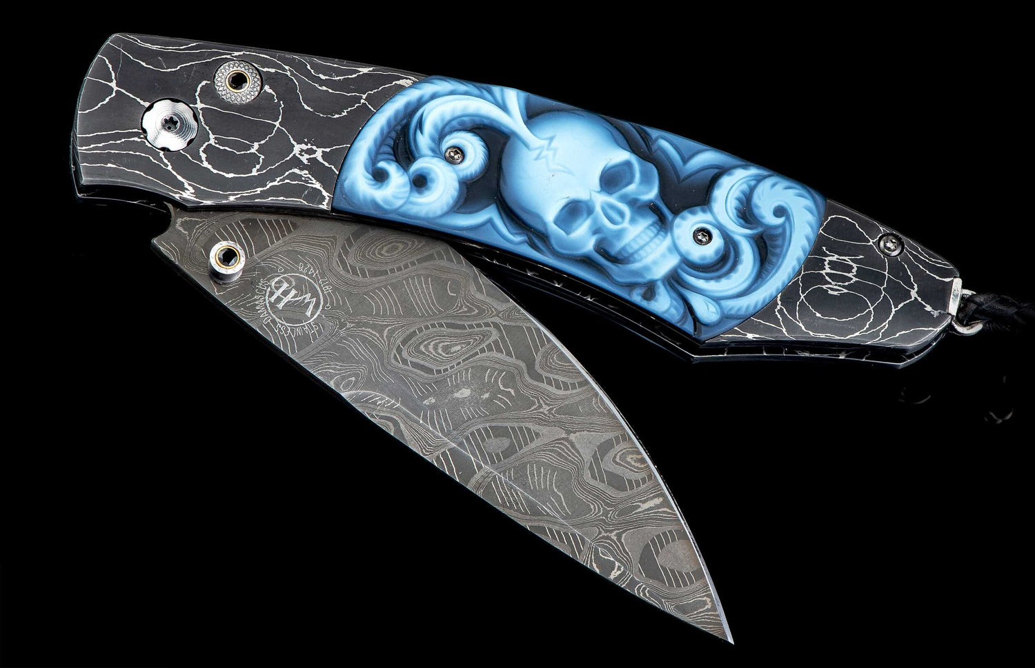 B12 Belfry folding knife with a black handle featuring white crackle patterns, a blue carved skull, and a Damascus steel blade.