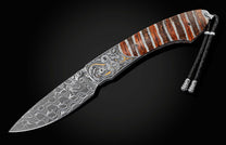 Damascus steel knife with silver and gold dragon engraving, striped handle, and black braided lanyard.
