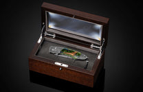 B12 Eagle II folding knife with a Damascus blade, green jade handle featuring a golden eagle inlay and blue accents, in an open wood display box.