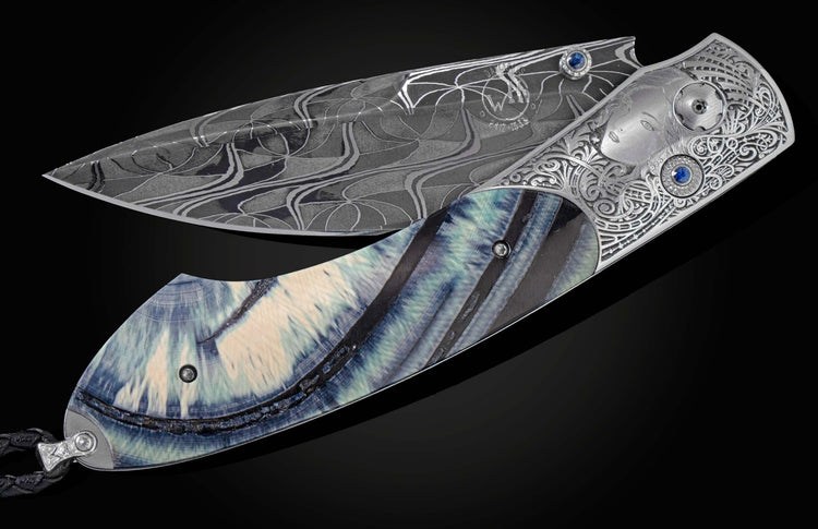 Handcrafted pocket knife from William Henry features a stainless steel frame, beautifully hand-engraved by Frederique Lepinois depicting a woman's face and intricate scrollwork inlayed with blue 10,000 year old ring cut fossil woolly mammoth tusk. The bla