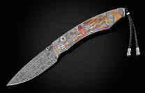 Handcrafted pocket knife from William Henry features beautiful color laser engraving of pirate scenes by Bottega Incisioni in Italy and set with spinel gemstones. The blade is damascus  steel.
