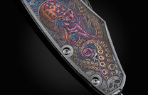 Handcrafted pocket knife from William Henry features beautiful color laser engraving of pirate scenes by Bottega Incisioni in Italy and set with spinel gemstones. The blade is damascus  steel.