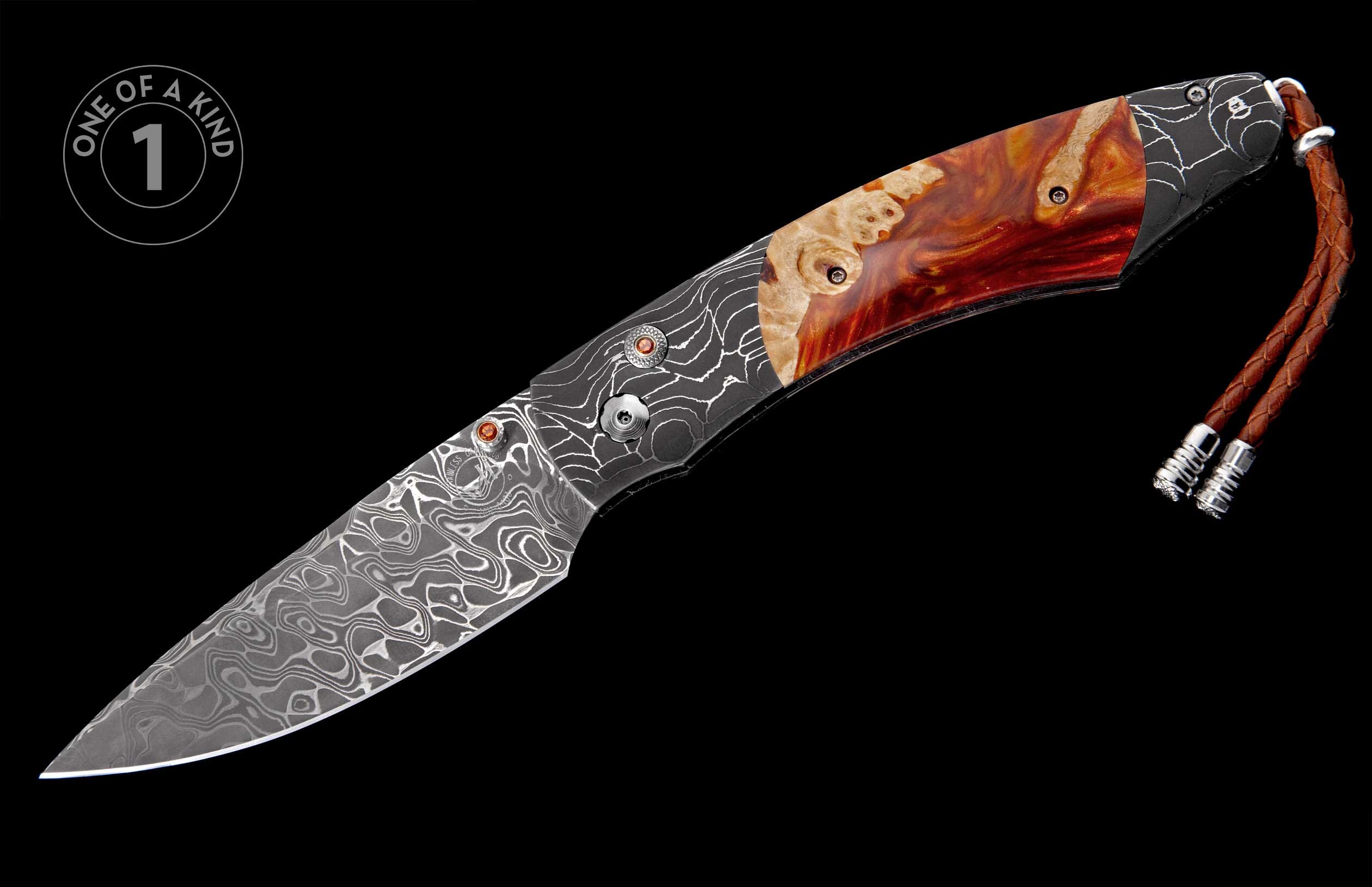 A unique folding knife with a Damascus steel blade, patterned metal, burl wood and red resin handle scales, red-orange inlays, and a braided leather lanyard.