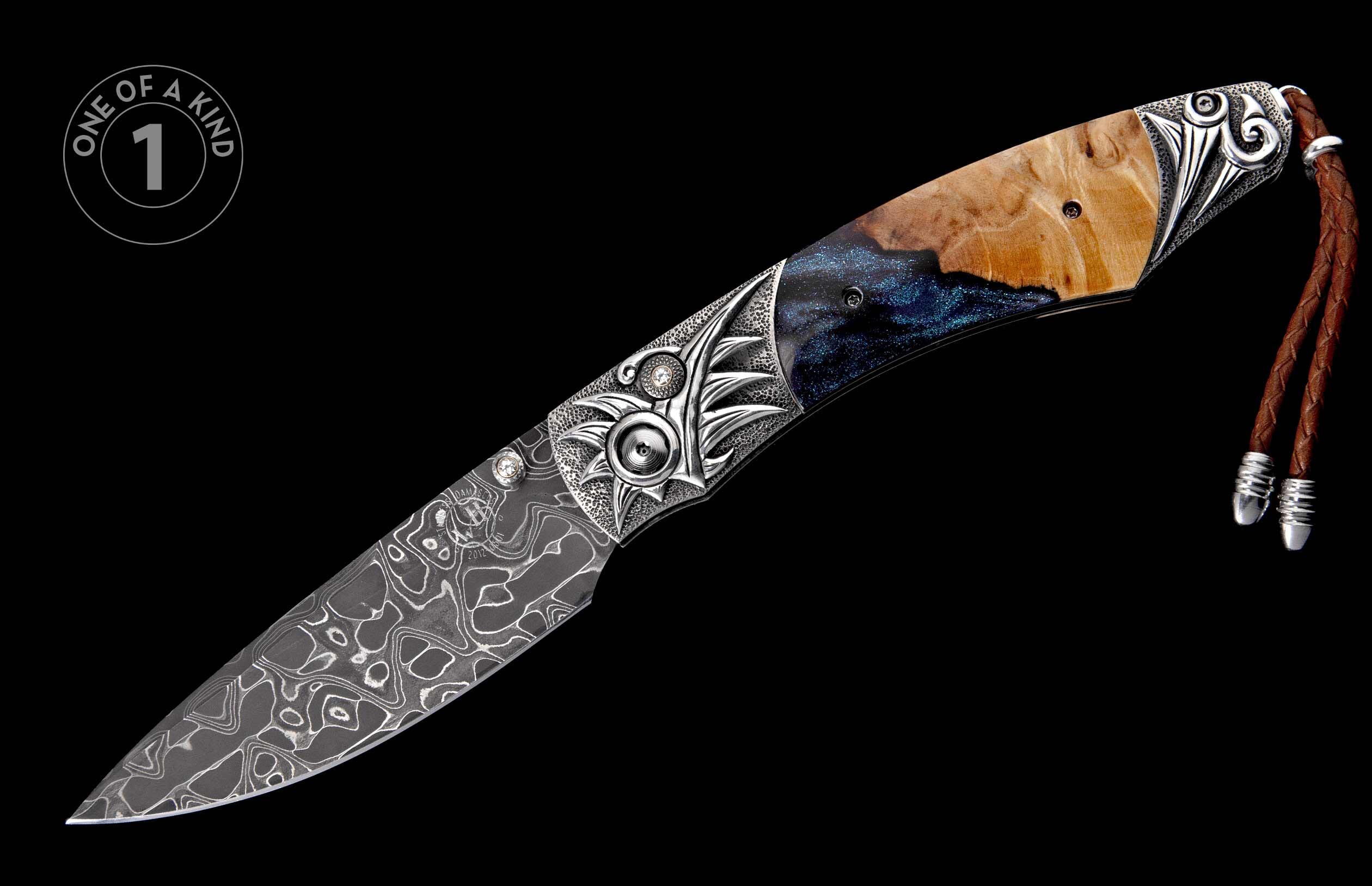 Folding knife with Damascus steel blade, carved silver bolster, sparkling blue resin and burl wood handle, and a brown leather lanyard.