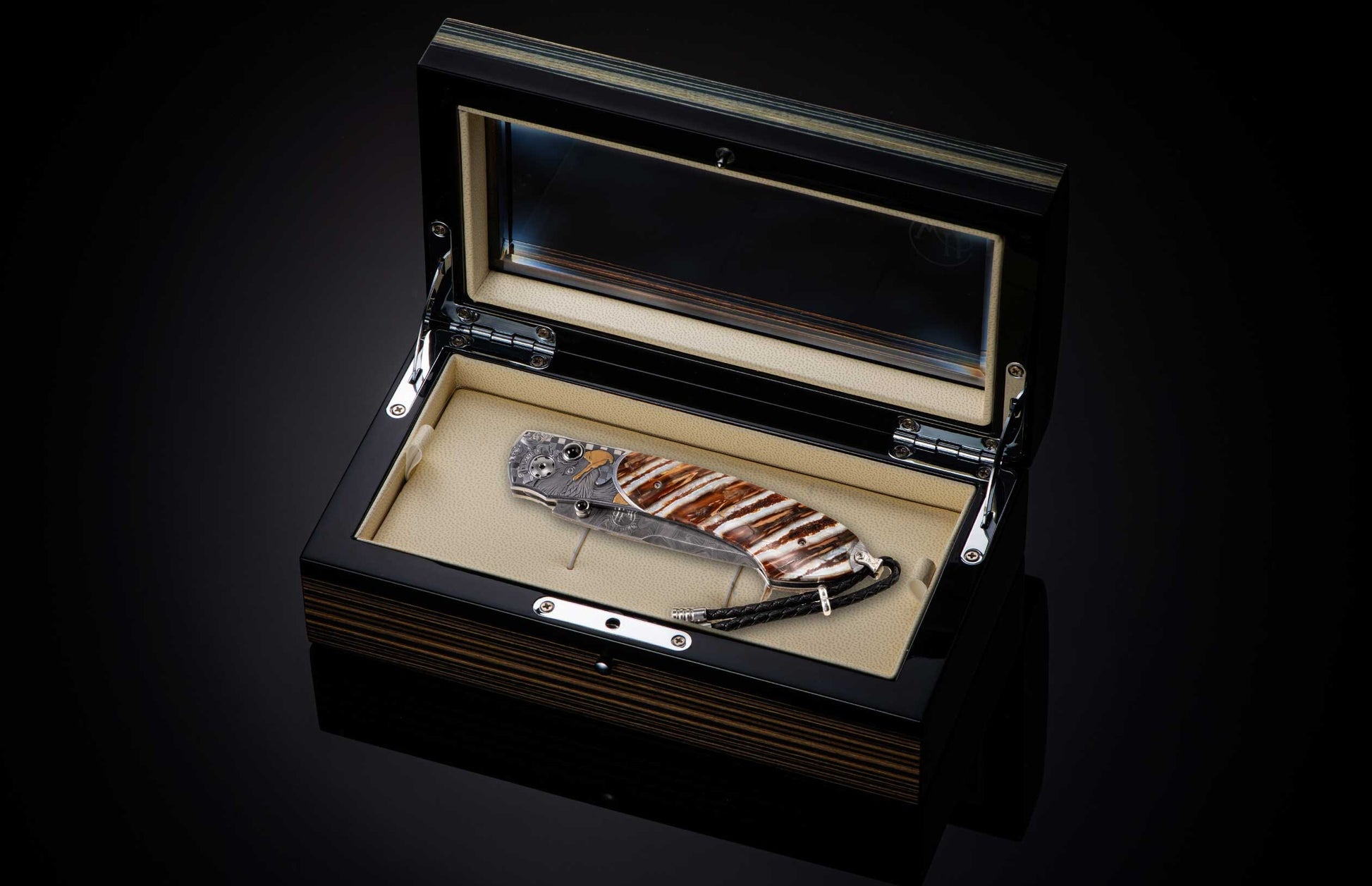Folding knife with a brown and white striped handle, eagle engraving, Damascus blade, and braided lanyard, displayed in an open dark wood grain box.