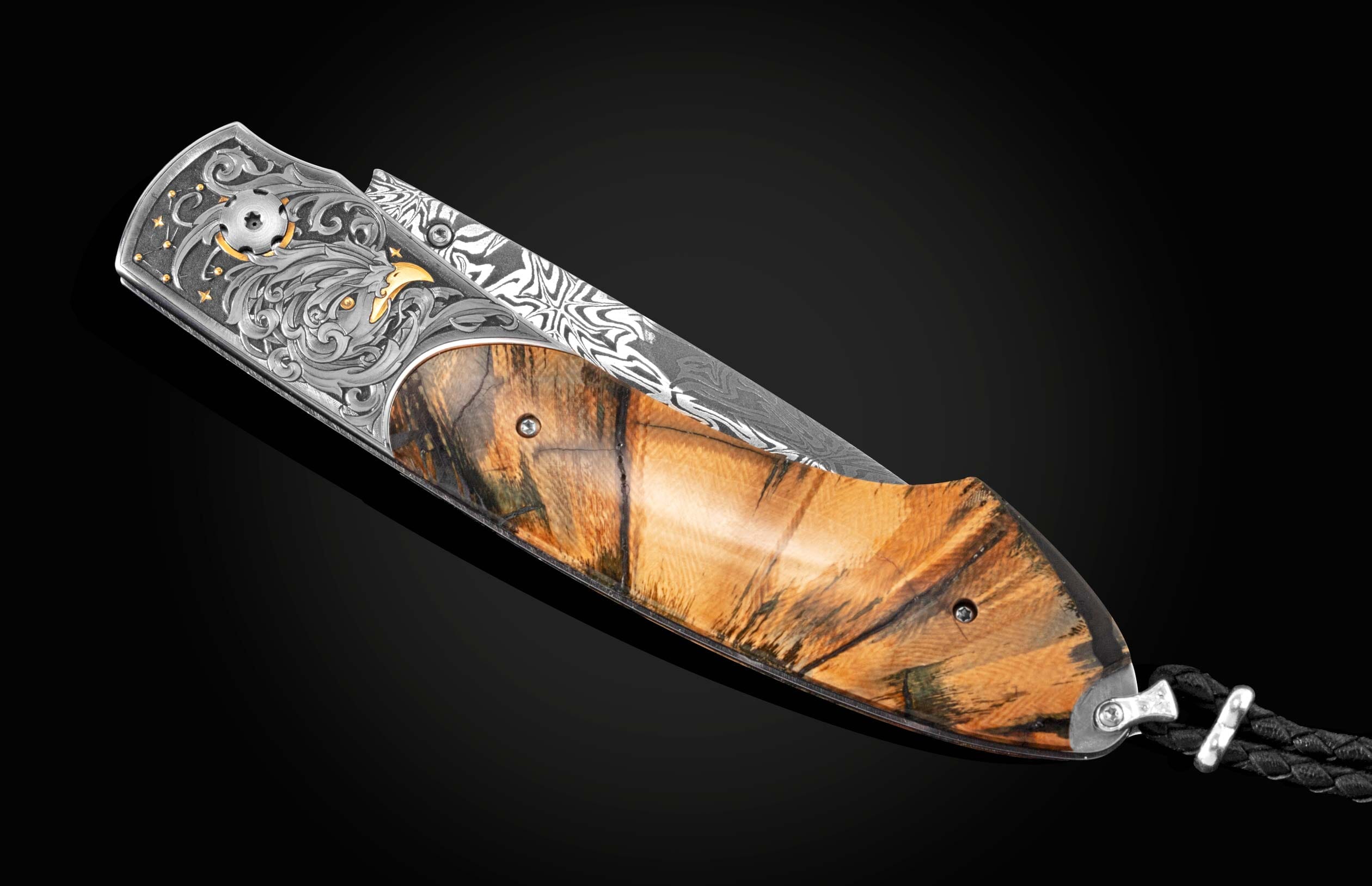 Handcrafted pocket knife from William Henry features hand-engraved bolsters with 24K yellow gold, 18K green and rose gold, and silver, inlaid with fossil Woolly Mammoth tusk and set with spinel gemstones. The blade is hand-forged  damascus steel.