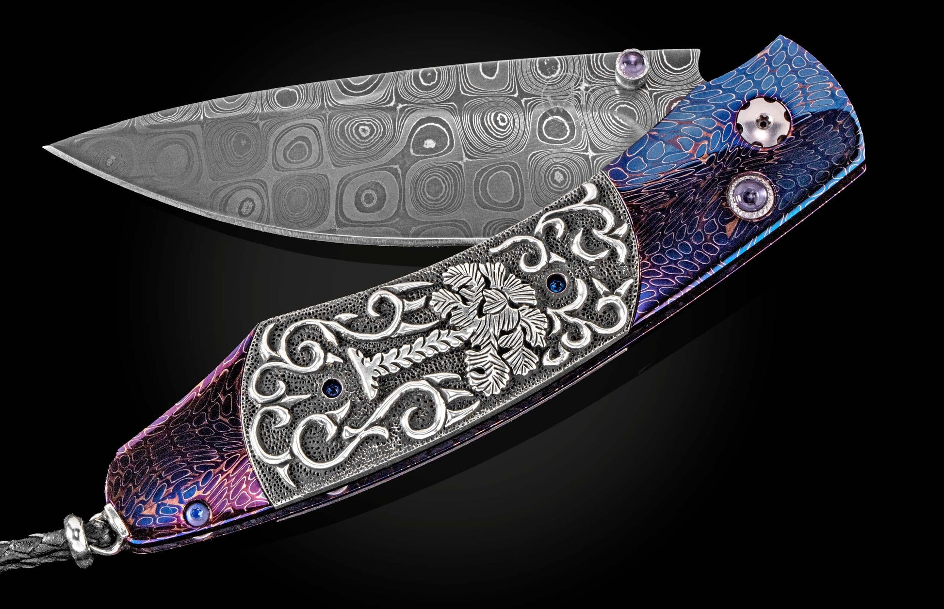 Ornate Damascus steel knife by SEWE featuring a purple and blue iridescent handle with intricate silver engraving, gemstone accents, and a braided leather lanyard, shown open.