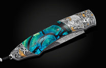 Handcrafted pocket knife from William Henry features hand-engraved skulls and decorative ornamentation with 24K gold and silver inlays and blue woolly mammoth tusk scales