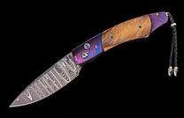 Folding knife with patterned Damascus blade, purple and blue handle with topographical swirls, light wood inlay, and braided leather lanyard.