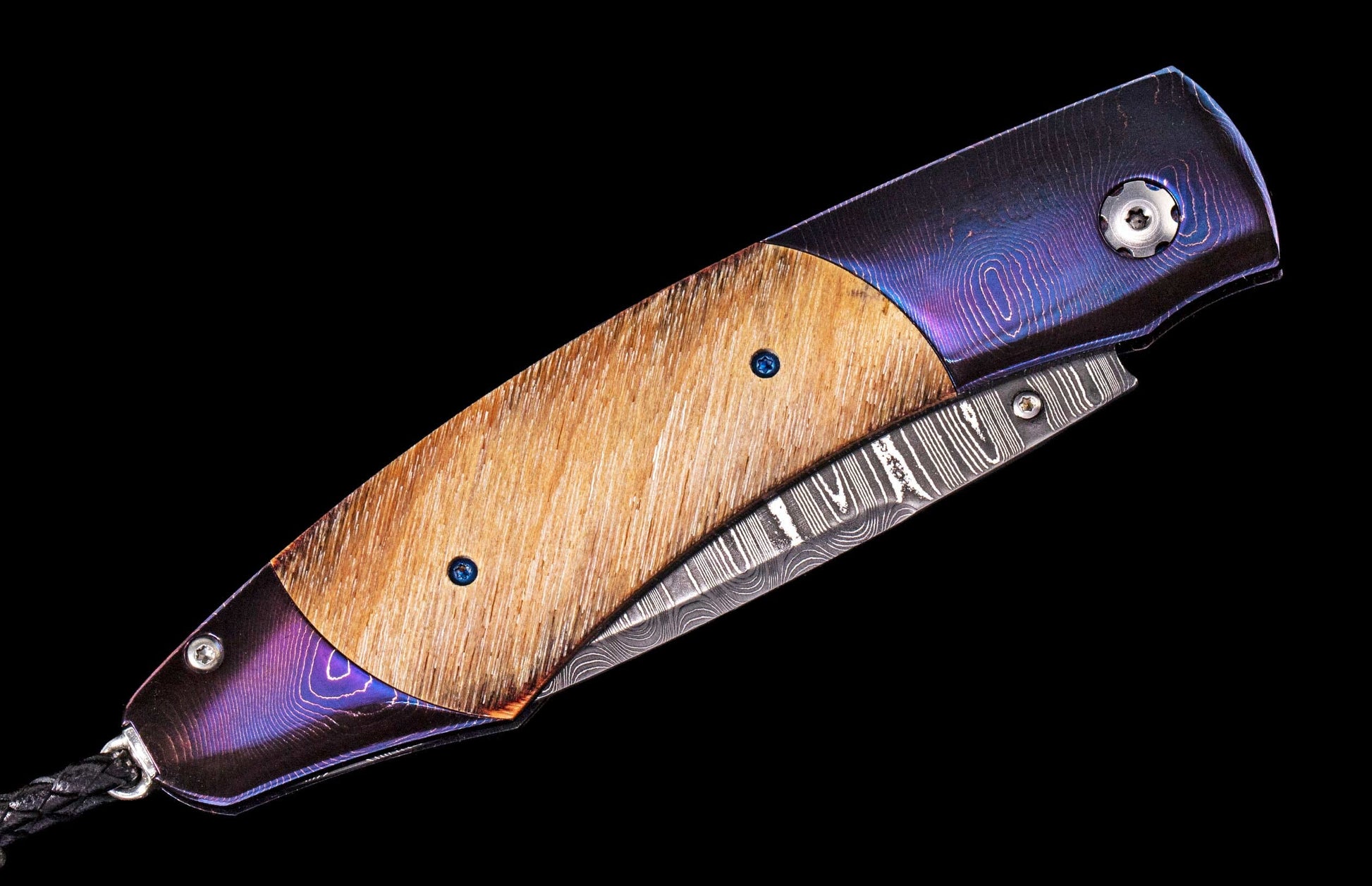 Folding knife with iridescent purple-blue handle and light brown wood scales, featuring a Damascus steel blade and black lanyard.