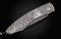 Engraved silver folding knife with ornate scrollwork, a cowboy riding a bull, a yellow horn inlay, and a visible patterned blade.