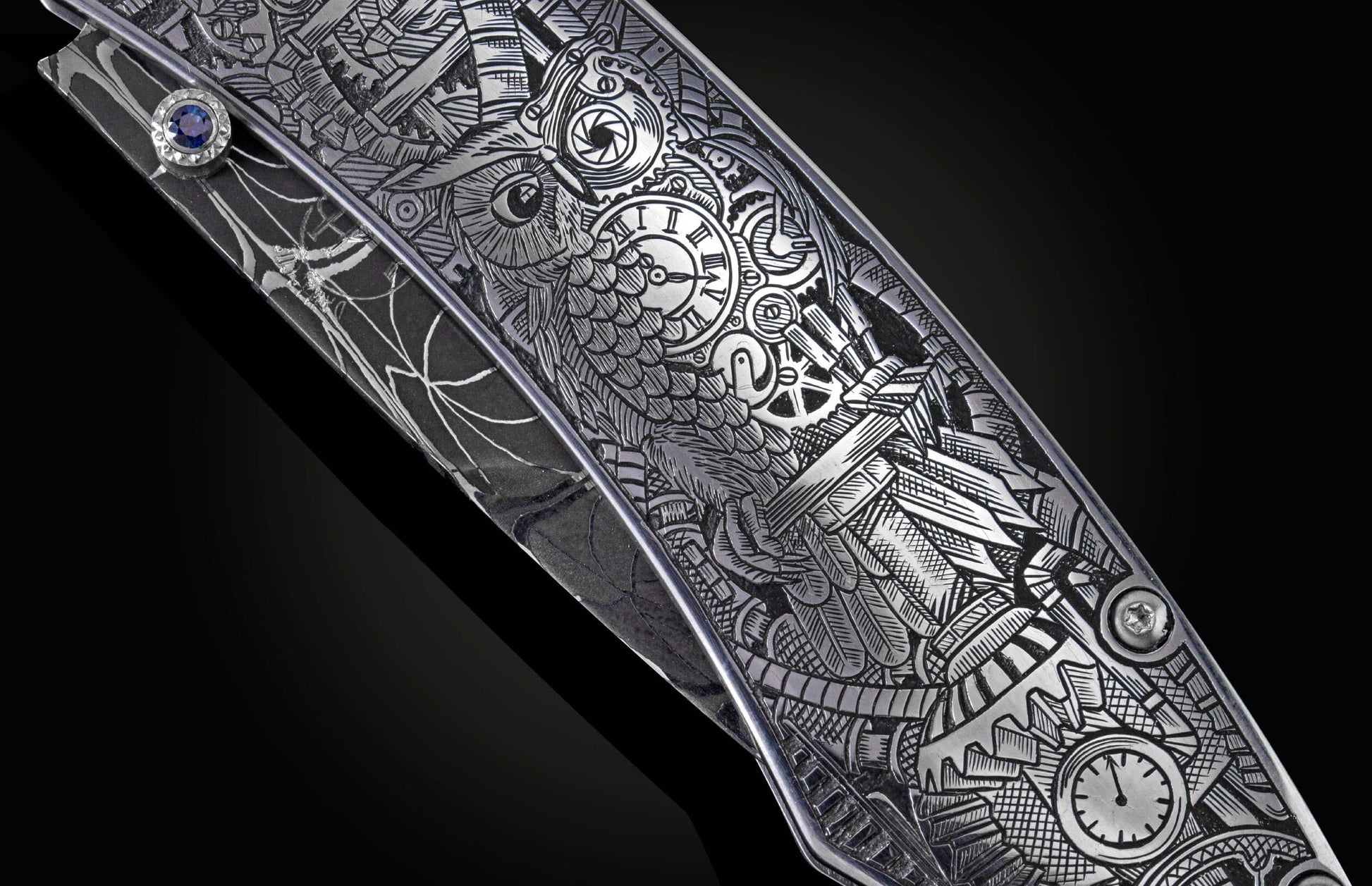 Knife with silver steampunk etching of an owl, gears, and clocks, on a dark Damascus steel handle with a blue sapphire.