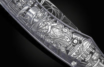 Silver-toned Steampunk knife with intricate engravings of gears, clocks, pipes, and a goggled bearded face, close-up.
