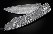 Handcrafted pocket knife from William Henry featuring an engraved tribal motif, a hand-forged Damascus steel blade, and spinel gemstones.