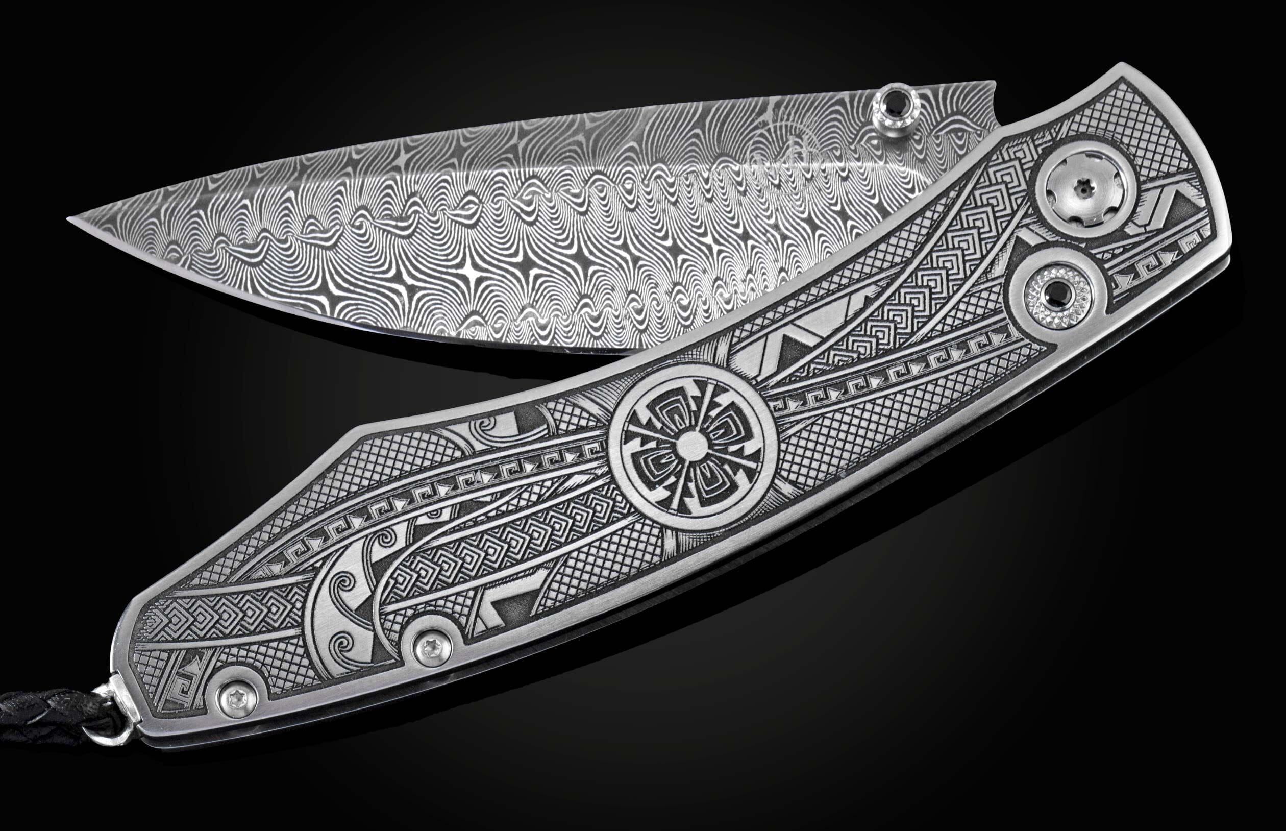 Handcrafted pocket knife from William Henry featuring an engraved tribal motif, a hand-forged Damascus steel blade, and spinel gemstones.