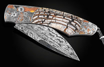 Handcrafted William Henry knife with hand engraved frame depicting a train robbery in 24K gold, copper, brass, and silver inlays by Narimantis Palsis, fossil Woolly Mammoth tusk, spinel gemstones, and a hand-forged damascus steel blade by Luke Mattern