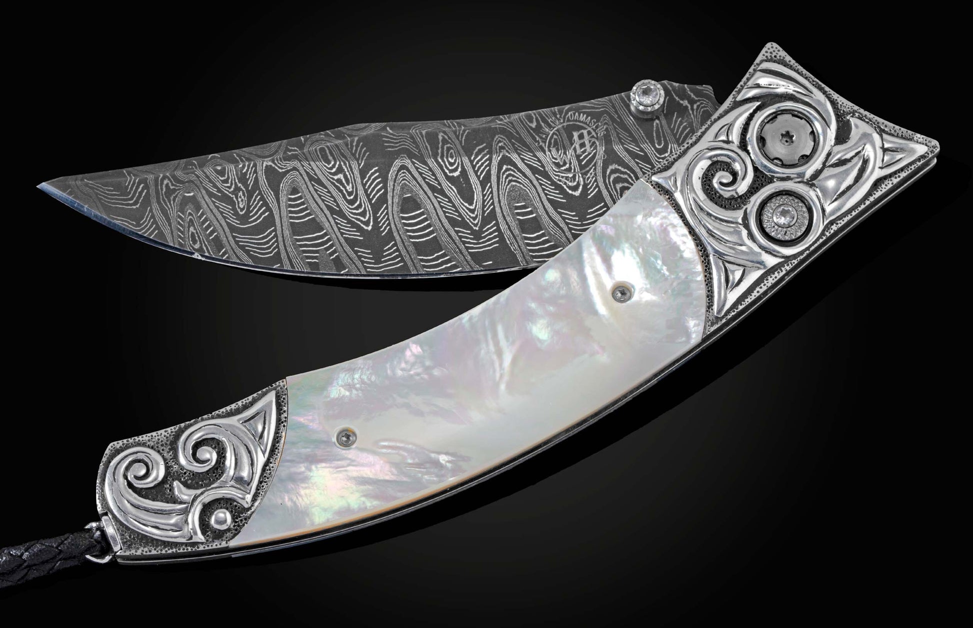 Handcrafted pocket knife from William Henry featuring a frame in hand-carved sterling silver inlaid with mother of pearl. The blade is hand-forged Damascus steel and the button lock and the thumb stud are set with white topaz gemstones. The knife is displ