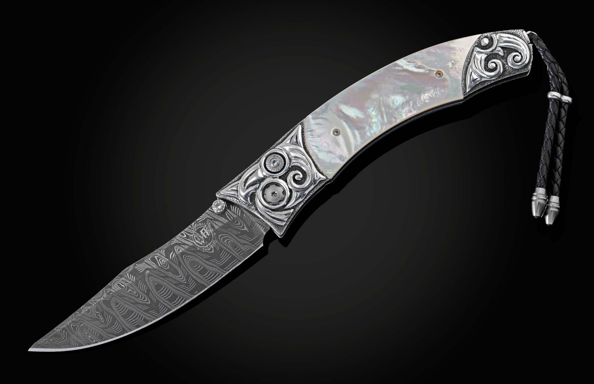 Handcrafted pocket knife from William Henry featuring a frame in hand-carved sterling silver inlaid with mother of pearl. The blade is hand-forged Damascus steel and the button lock and the thumb stud are set with white topaz gemstones. The knife is displ