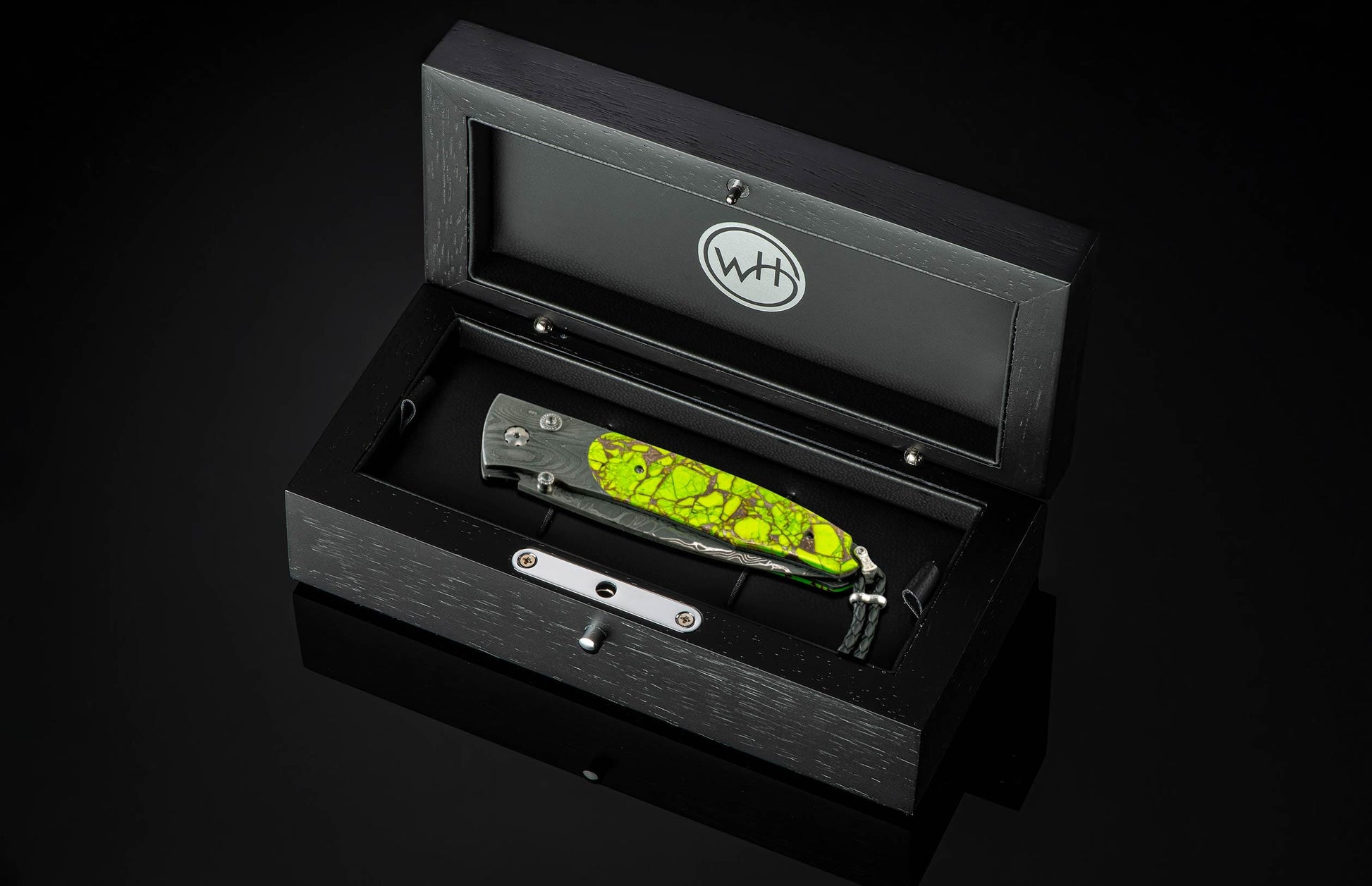 Folding knife with a Damascus steel blade and lime green textured handle, presented in an open black wooden box with a 'WH' logo.