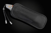 B30 Washington knife with a silver eagle handle and braided lanyard, partially in a black pebbled leather sheath with an embossed logo.