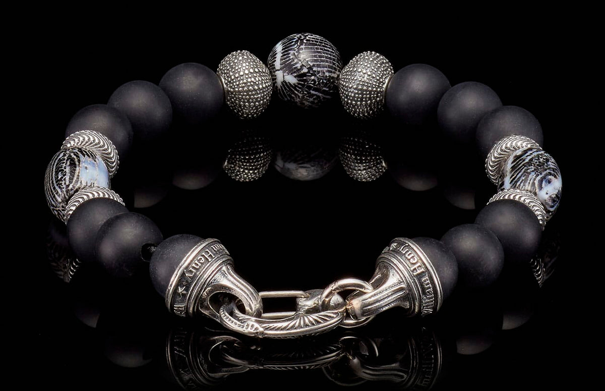 Black matte bead bracelet by William Henry, featuring ornate sterling silver spacers, a patterned bead, and an engraved clasp.