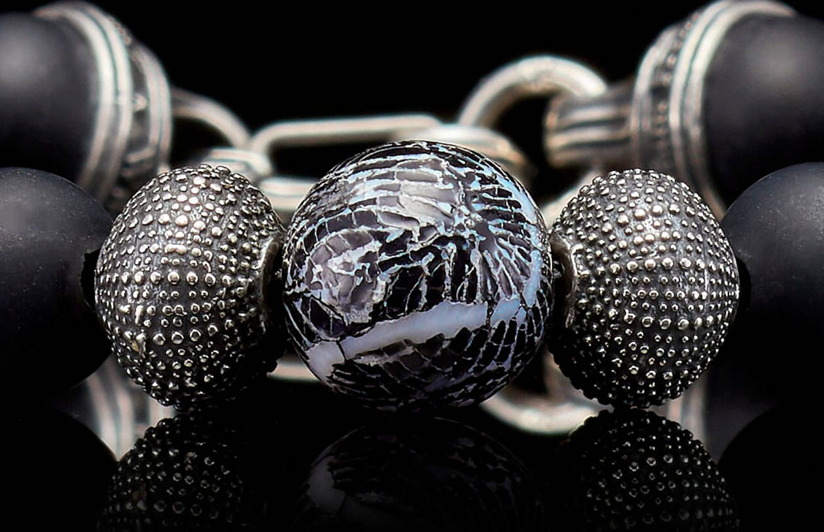 Beaded bracelet with a cracked black and white central bead, textured silver, and matte black beads.