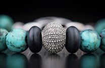 Beaded bracelet with a textured silver bead, smooth black beads, and mottled turquoise beads.