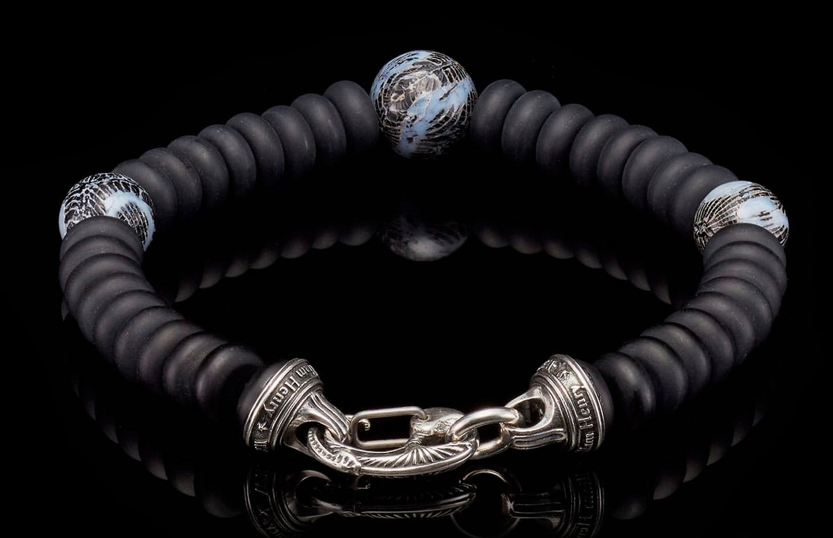 Black matte disc bead bracelet with three abstract blue/white patterned beads and an ornate silver clasp engraved "Tim Henry".