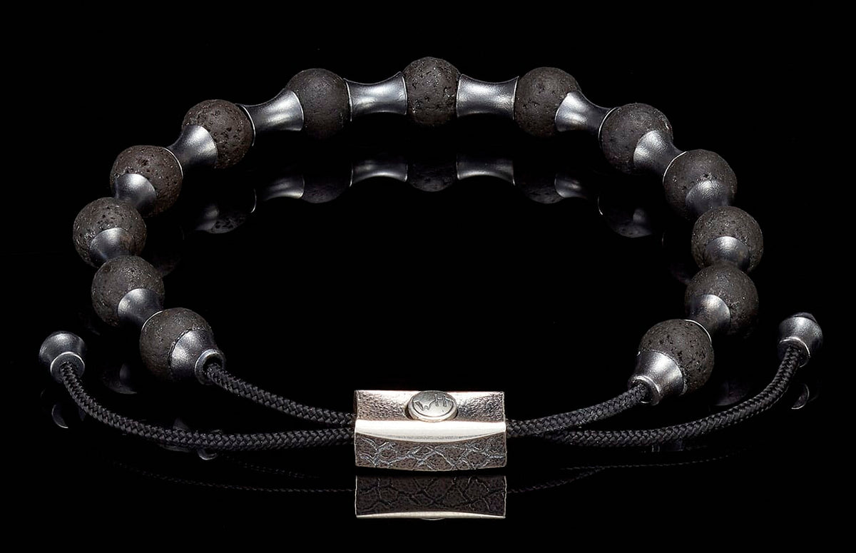 Black lava stone beaded bracelet with silver-tone spacers, a textured silver clasp, and adjustable black cord.