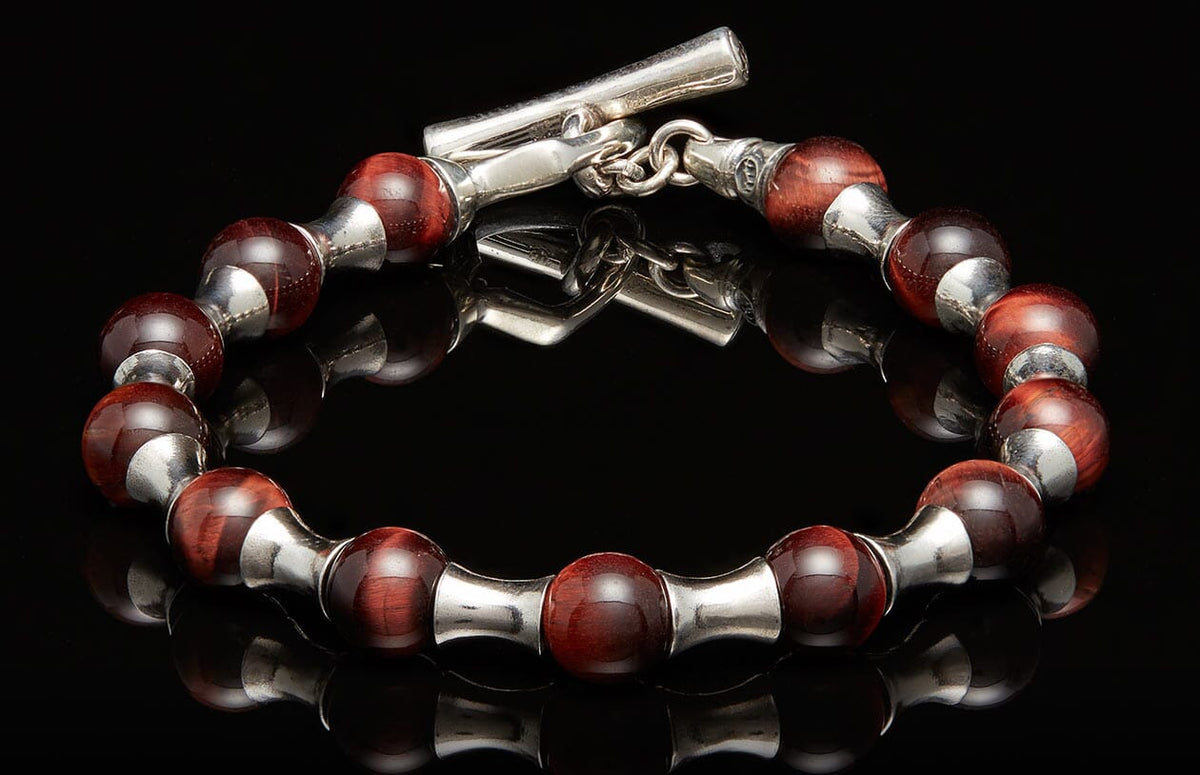 Deep red beaded bracelet with silver-toned metal spacers, a toggle clasp, and subtle striations on the beads.