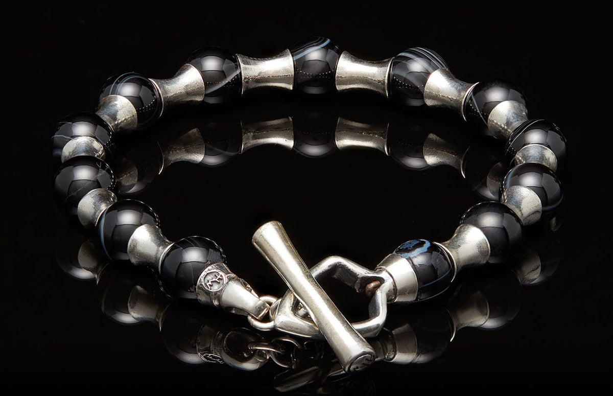 Black agate bead bracelet with silver barrel separators and a decorative animal head toggle clasp.