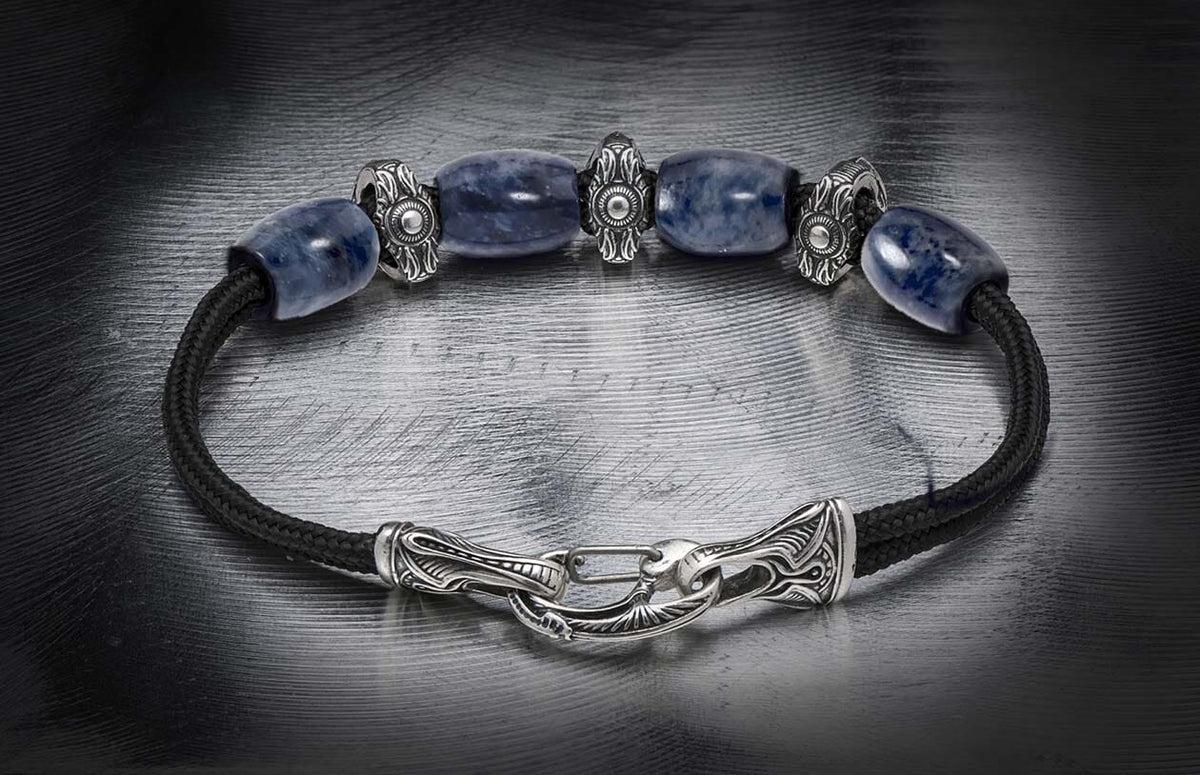 Blue sodalite bracelet with black braided cord and ornate silver-toned beads and a decorative hook clasp.