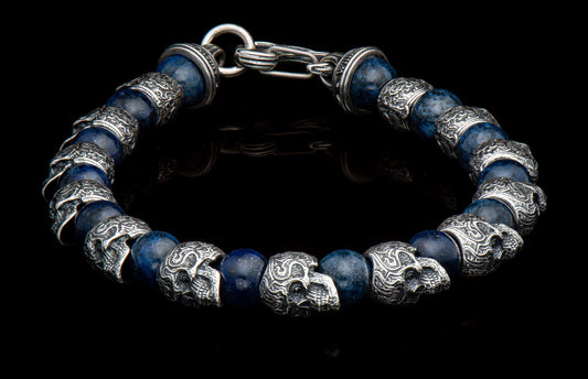 Dark blue stone beaded bracelet featuring ornate silver skull beads and a silver toggle clasp.