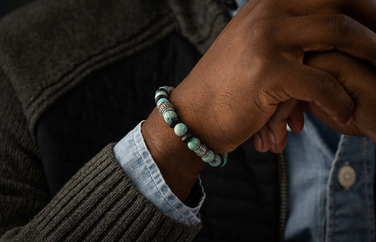 Newport blue agate and black beaded bracelet with silver filigree on a dark-skinned wrist, wearing a grey sweater.
