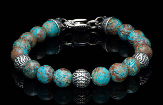Blue Agate bracelet with marbled blue and brown beads, featuring patterned silver beads and an ornate silver clasp, reflecting on a dark surface.
