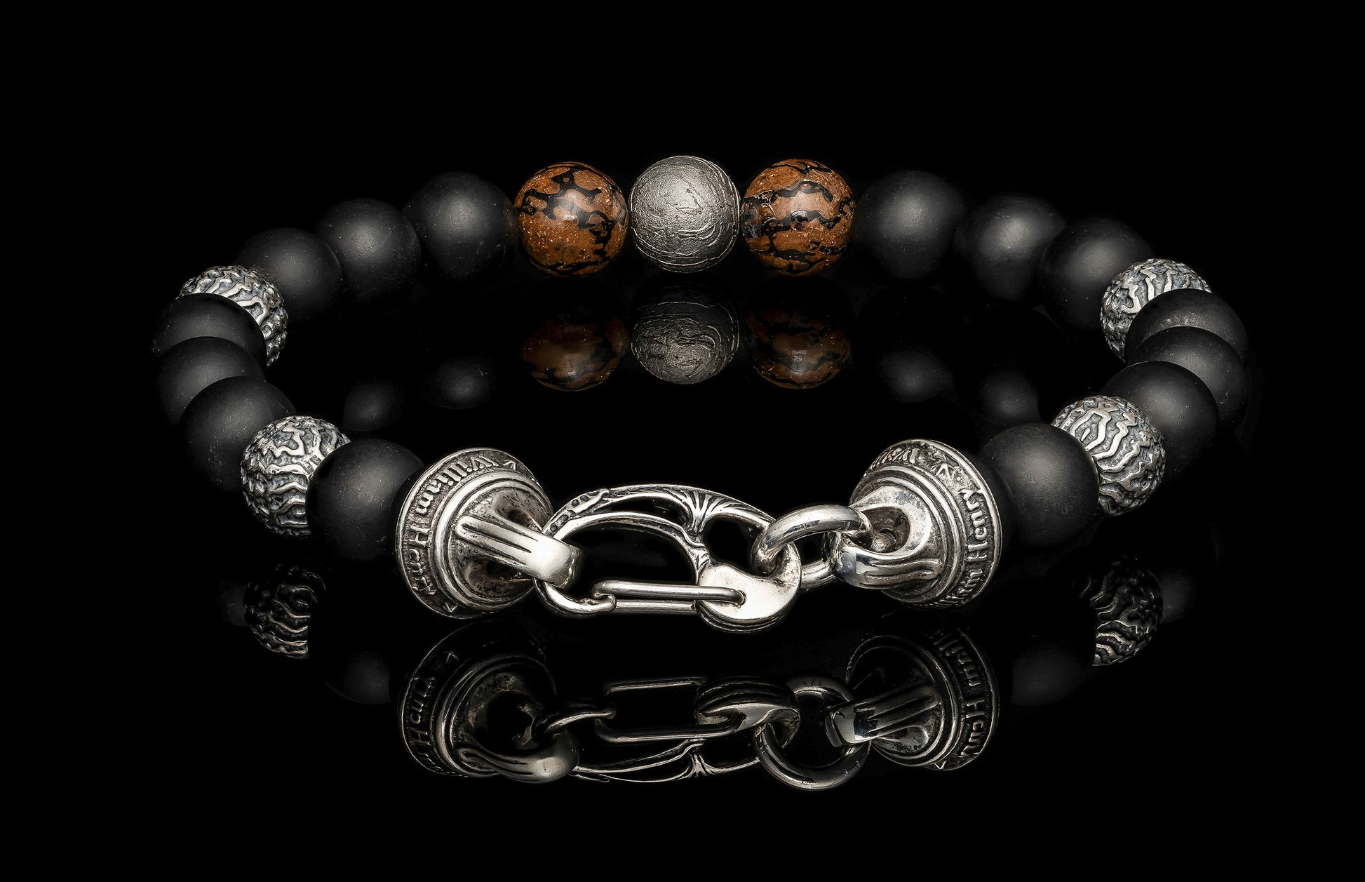 Beaded bracelet with meteorite, dinosaur bone, silver and onyx beads on a dark background