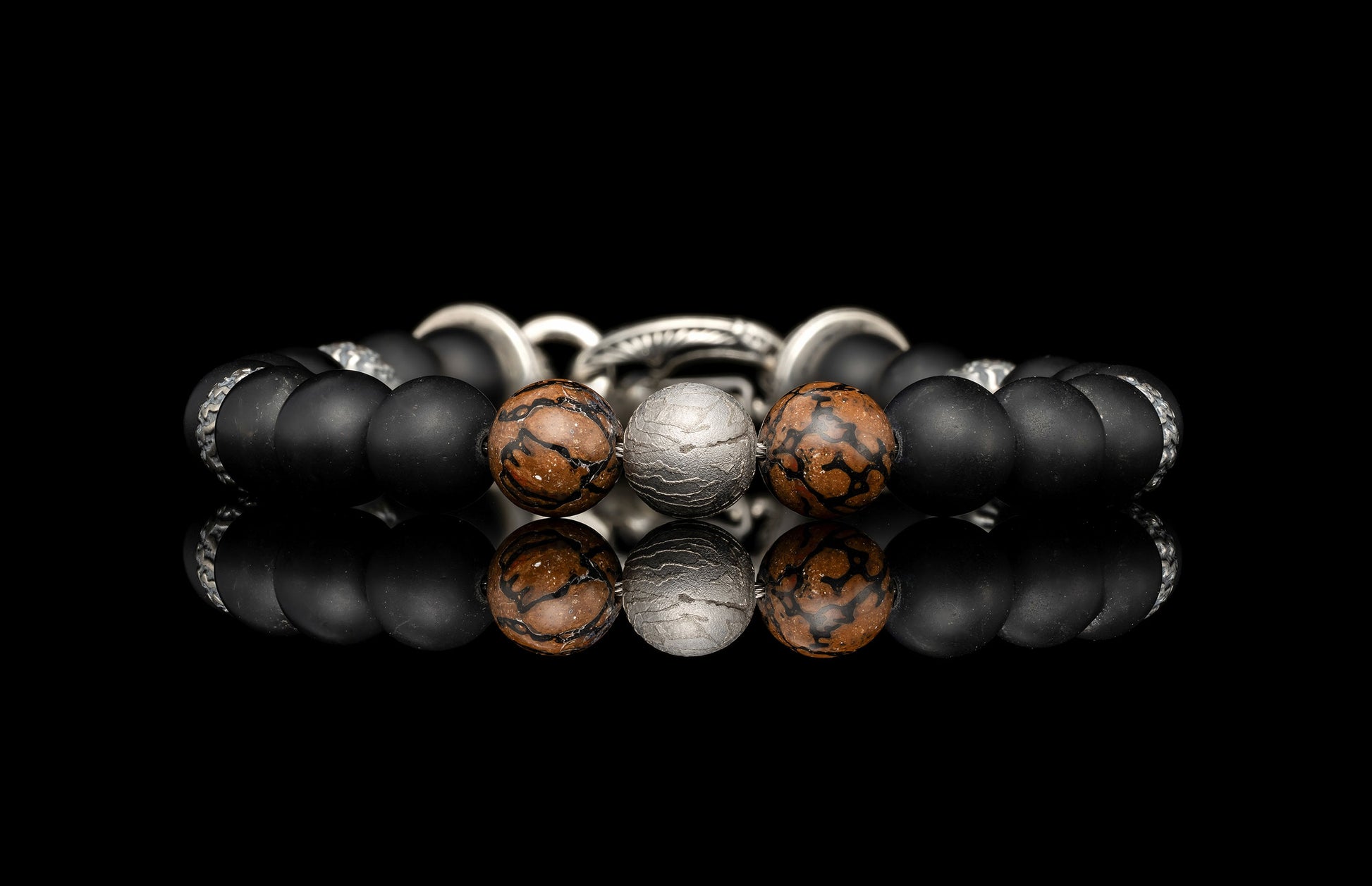 Beaded bracelet with meteorite, dinosaur bone, silver and onyx beads on a dark background