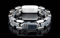 Silver chunky link bracelet with polished and brushed texture, featuring a circular logo and 925 stamp on the clasp, displayed on a reflective black surface.