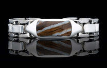 A polished silver link bracelet with a prominent rectangular brown and white striped stone inlay, shown on a reflective black surface.