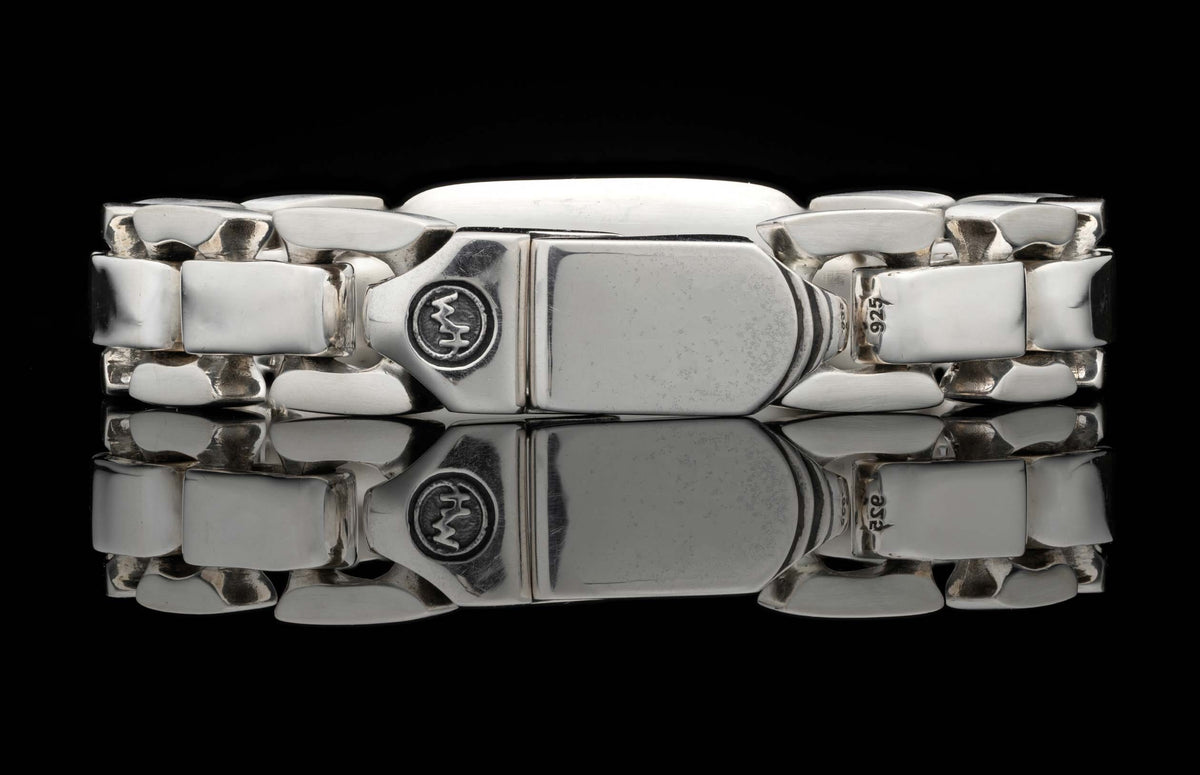 Silver identity bracelet with chunky rectangular links and a prominent clasp engraved with 'WM' and '925'.