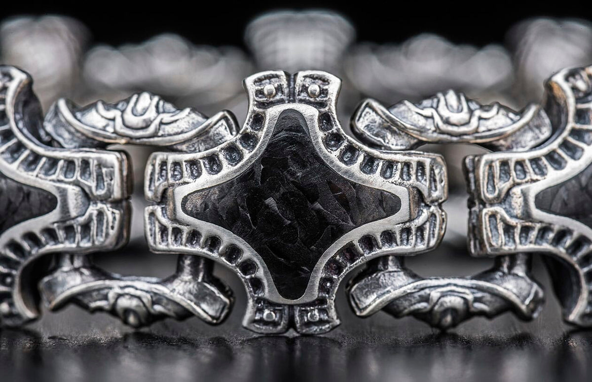 Ornate silver metal jewelry link with a distressed finish and a black textured rhombus-shaped insert, shown in close-up.