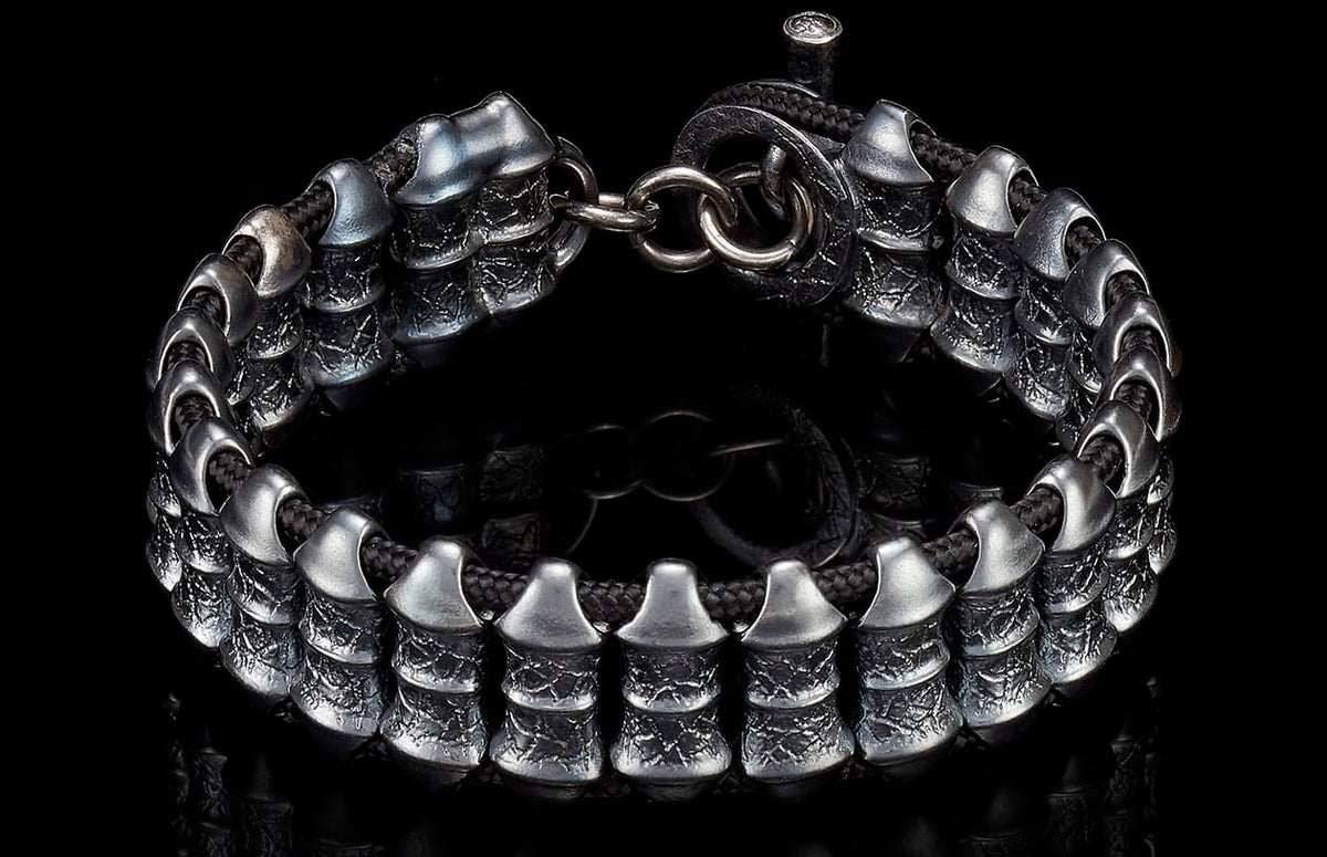 Textured dark silver bracelet with unique tiered metal beads on a black cord and ring clasp.