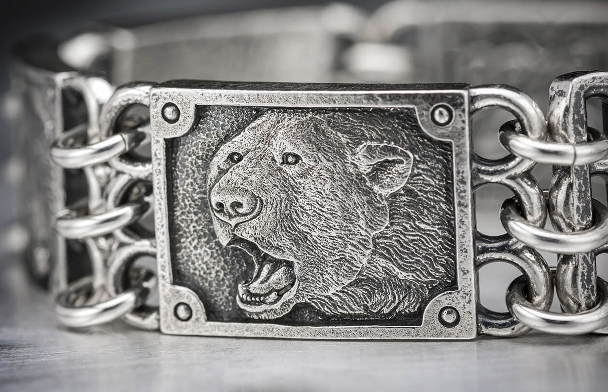 Oxidized silver bracelet featuring a roaring bear's head relief on a central plaque, linked by textured metal chains.