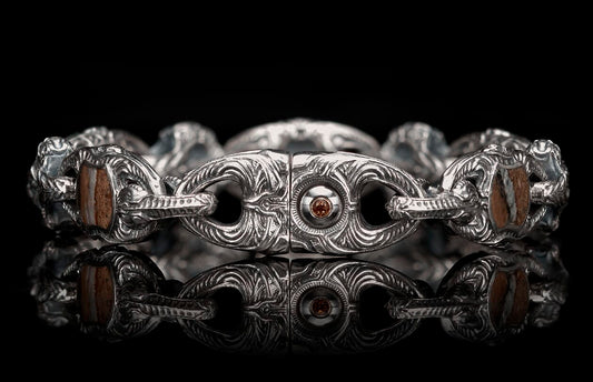 Ornate silver bracelet with intricate carved links, rectangular brown stone inserts, and a central amber-colored gem.