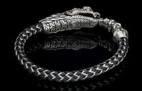 Black and silver braided bracelet with a detailed dragon head clasp, red eyes, and a reflective surface.