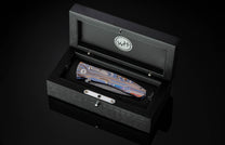 Handcrafted pocketknife from William Henry features a light and resilient titanium frame that is laser-engraved in swirls of color. The blade is hand-forged damascus steel. The button lock and thumb stud are inset with citrine gemstones.